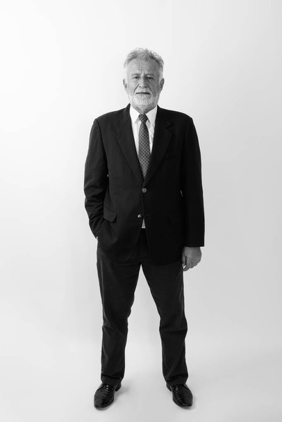 Full body shot of handsome senior bearded businessman standing against white background - Foto, Bild