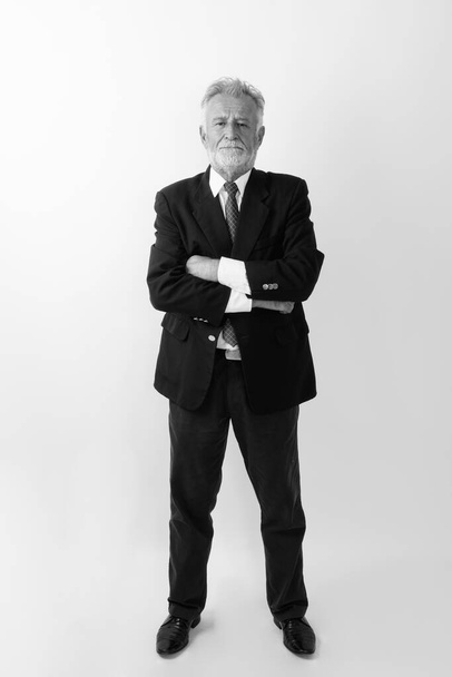 Ganzkörperaufnahme eines gutaussehenden bärtigen Geschäftsmannes, der mit verschränkten Armen vor weißem Hintergrund steht - Foto, Bild