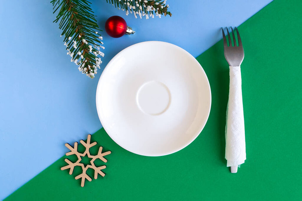 Empty plate and Christmas decoration on color geometric background, copy space for the text, minimal concept - Photo, Image