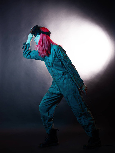 young woman with pink hair and in a jumpsuit uses virtual reality glasses, is in the game, - Фото, зображення