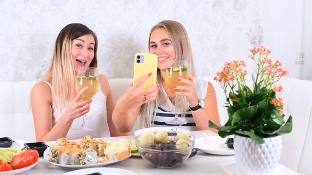 Δύο ευχαριστημένοι φίλοι μοιράζονται online περιεχόμενο χρησιμοποιώντας smartphone στο σπίτι, επιλεκτική εστίαση - Φωτογραφία, εικόνα