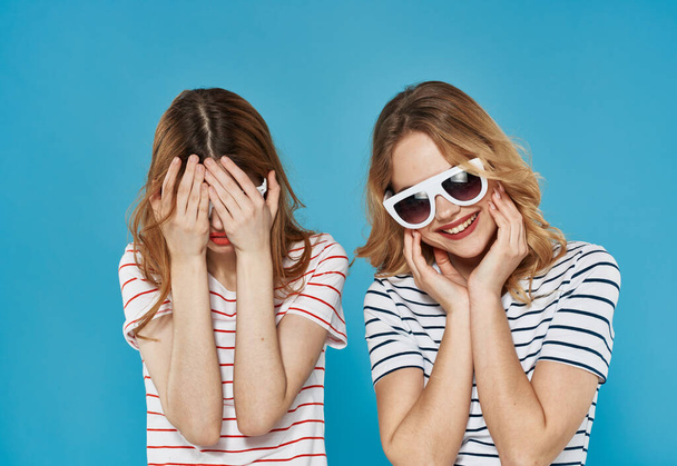 two cheerful girlfriends in striped t-shirts sunglasses hug friendship  - Photo, Image
