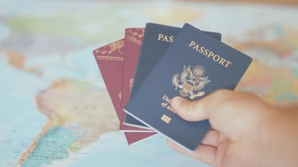 カラフルな世界地図の前でアメリカとスウェーデンのパスポートを保持する手 - 映像、動画