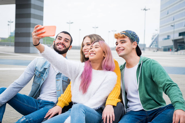 Group of young friends taking a selfie in the city - Happy millennials sharing content on social media - People, technology and lifestyle - 写真・画像