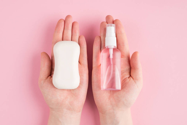 Top above overhead pov first person close up view photo of hands holding soap and sanitizer isolated on pastel pink color background with copyspace - Photo, Image