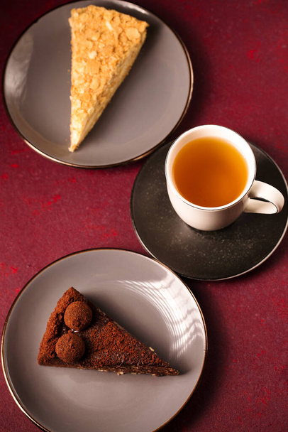 різні торти з чашкою чаю на бордовому фоні
 - Фото, зображення
