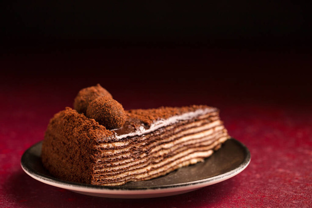 Σπάρτακος πολυστρωματικό κέικ σοκολάτας σε ένα μπορντό φόντο - Φωτογραφία, εικόνα