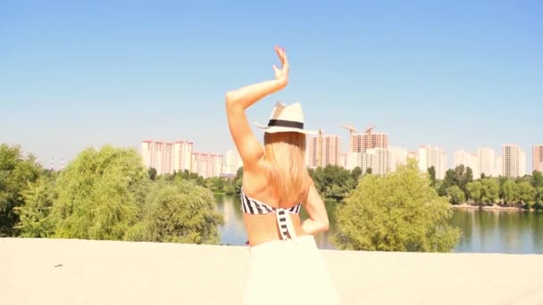 Γυναίκα με καπέλο και σκούρα γυαλιά χορεύει στη φύση έξω από την πόλη - Πλάνα, βίντεο