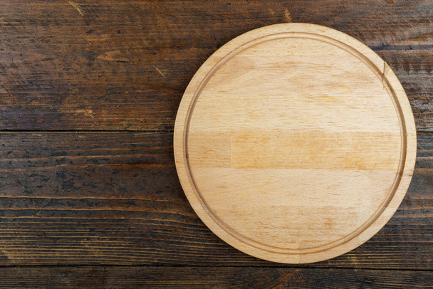 Round cutting board on a wooden table. Space for text. Top View. - Фото, изображение