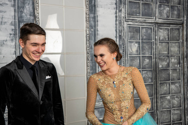 молодая пара в вечерних танцевальных костюмах позирует в танцевальном зале - Фото, изображение