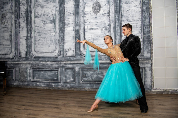 молодая пара в вечерних танцевальных костюмах позирует в танцевальном зале - Фото, изображение