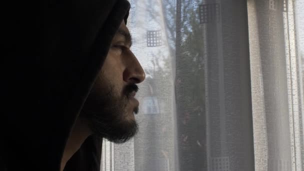 Kapüşonlu bir erkek tecrit sırasında pencereden dışarı dalgın dalgın bakıyor. Kilitli, Yan Görünüm - Video, Çekim