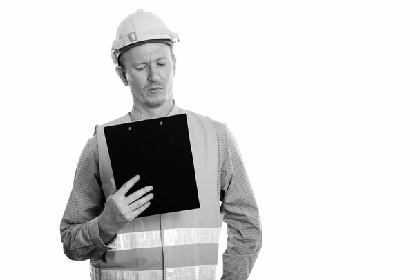 Studio shot of man construction worker reading on clipboard - Photo, Image