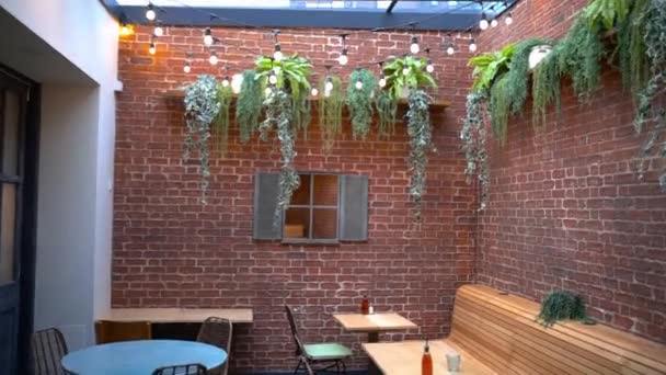 Plantas colgando de las paredes de ladrillo de un restaurante vegano con techo de cristal - Metraje, vídeo