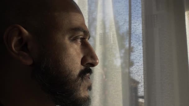 Dorosły UK Azjatycki mężczyzna wyglądający przez okno w zamyślonym nastroju. Zamknięte, widok z boku - Materiał filmowy, wideo