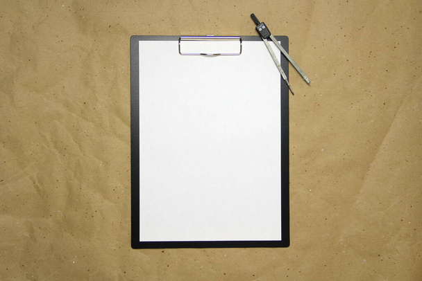 A tablet with a white sheet of A4 format with divivder on a beige craft paper. Concept of accurate measurements, study and construction. Stock photo with empty place for your text and design. - Fotografie, Obrázek