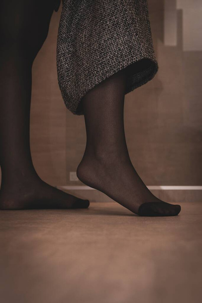 Портрет ноги в сексуальных черных колготках девушки, задирающей юбку. Нейлон укреплен на ногах. - Фото, изображение