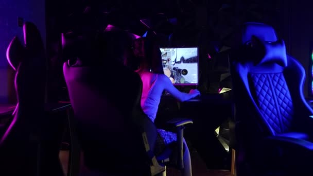 Een jonge vrouw zit in een stoel in gaming club en het spelen van een shooter spel - Video