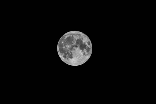 Um retrato de uma lua cheia brilhando à noite na escuridão do espaço sem fim. - Foto, Imagem
