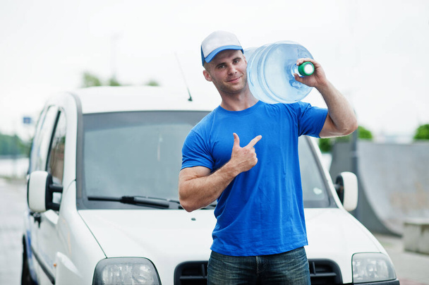 Delivery man in front cargo van delivering bottles of water showing finger. - Foto, Imagen