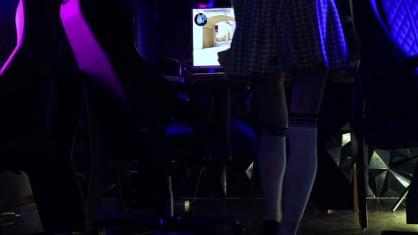 Joven mujer sexy viene a la computadora en un club de informática y tira de los calcetines de golf y luego se sienta en la silla - Imágenes, Vídeo