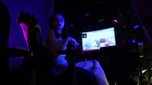 Jeune femme sexy assise dans un club de jeu et jouant avec de la gomme à bulles dans sa bouche - Séquence, vidéo