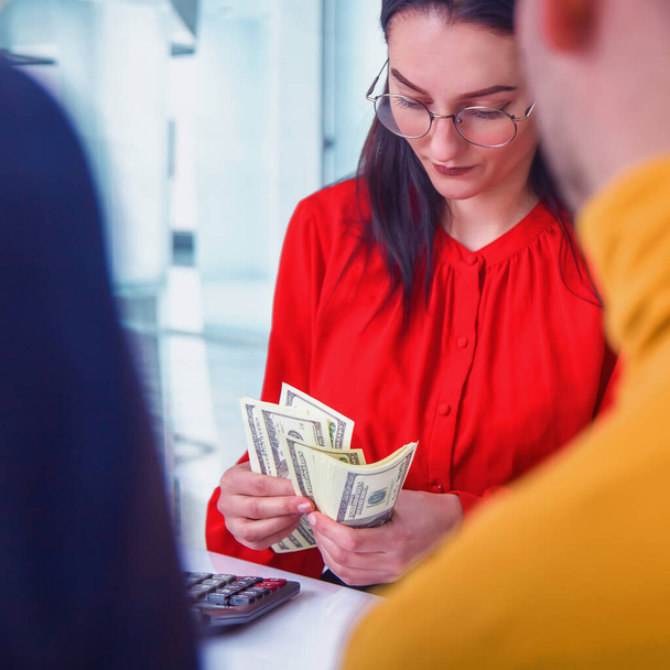 Metaphors photo of young business people holding money and analyzing financial balance of company. Stock market, office, tax, concept. Close up. - Photo, Image