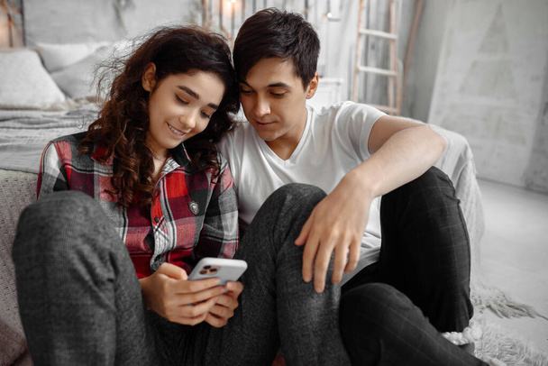 Mutlu genç çift akıllı telefonları birlikte kullanıyor. - Fotoğraf, Görsel