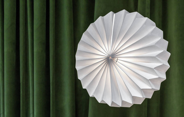 Round corrugated lamp against a background of green curtains. - Photo, Image