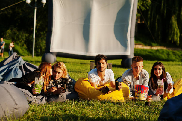 Young multi ethnic group of people watching movie at poof in open air cinema. - Foto, Imagem