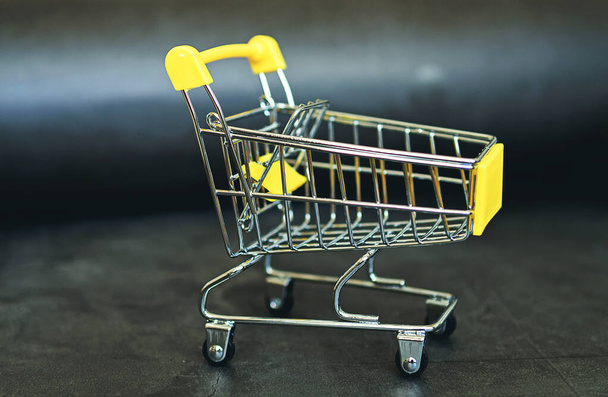 shopping carts on the wooden floor. isolated on white backgroundFood cart on a dark background. Creative idea for a sale, promotion, or concept for cyber Monday or black Friday - Φωτογραφία, εικόνα