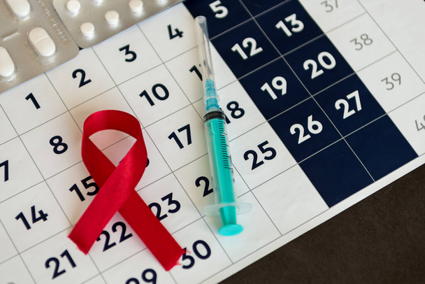 Welt-AIDS-Tag. Rote Schleife, medizinische Spritze und Kalender. Gesundheits- und Medizinkonzept - Foto, Bild