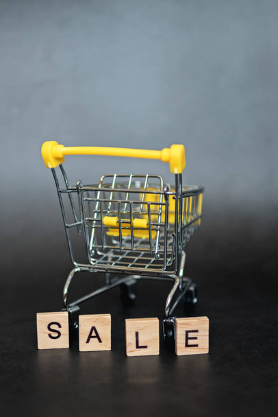 Season of sales in online stores. Cart and sales word on dark blue background. Creative idea for a sale, promotion, or concept for cyber Monday or black Friday - Foto, Imagem