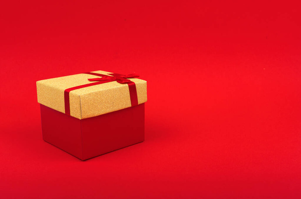 red square gift box with gold cover on red background, minimalism, new year gift. - Фото, изображение