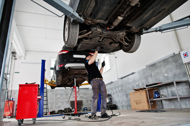 Car repair and maintenance theme. Mechanic in uniform working in auto service.  - Foto, Bild