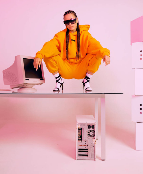 Stylish asian female office worker with obsolete computer squats on desk. Colored Neon light - Φωτογραφία, εικόνα