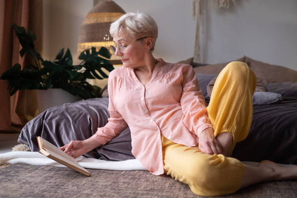 Старшая белая женщина дома читает книгу - Фото, изображение