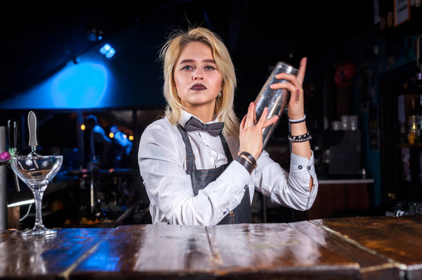 Focused kobieta mixologist umieszcza wykończenie dotyka drinka stojąc w pobliżu lady bar w pubie - Zdjęcie, obraz