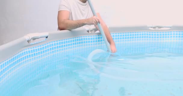 Мужчина собирает очистители бассейна, а также обслуживает и обслуживает бассейн - Кадры, видео