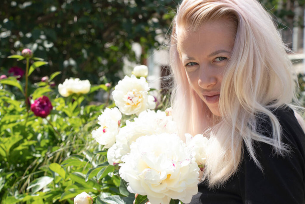 Юна українська блондинка біля квітів у саду. - Фото, зображення