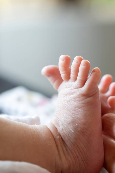 Ένα κοντινό πορτραίτο κάποιων μικρών ποδιών. Το νεογέννητο παιδί τεντώνει τα μικρά χαριτωμένα δάχτυλα των ποδιών του στο όριο. - Φωτογραφία, εικόνα