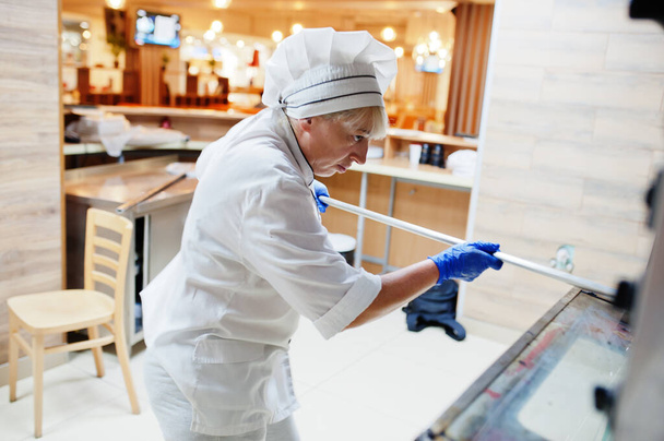 Female chef preparing pizza in restaurant kitchen. - Zdjęcie, obraz
