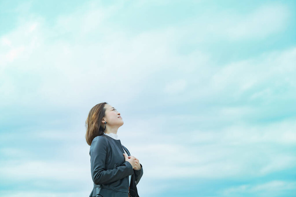 Випадково одягнена азіатська бізнес-леді дивиться в небо
 - Фото, зображення