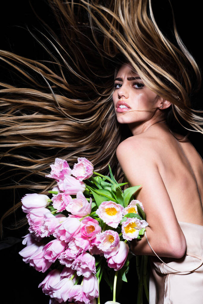 Sensual girl with tulips flowers bouquet isolated on black. Hair in motion. Fashion haircut, vogue hairstyle. - Foto, Bild