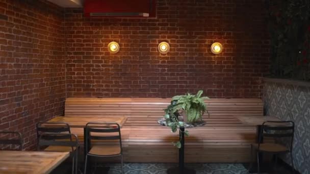 Tables, chairs, and three lights on a red brick wall from a vegan restaurant - Materiaali, video