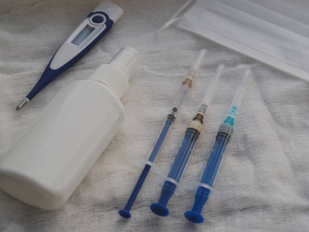 Medizinische Spritze, elektronisches Thermometer, medizinische Maske, Einmalhandschuhe und Antiseptikum auf weißem Hintergrund - Foto, Bild