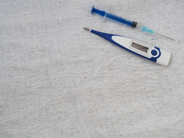 Medizinische Spritze und elektronisches Thermometer auf weißem Hintergrund - Foto, Bild