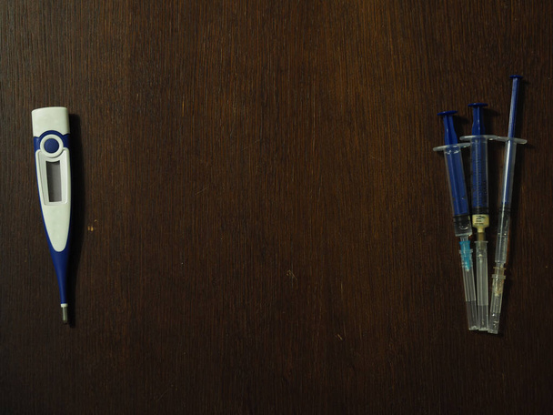 Medical syringe and electronic thermometer on a black background - Zdjęcie, obraz