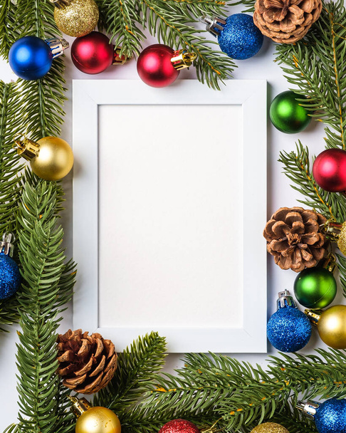 Vánoční kompozice s prázdným rámečkem. Barevné kulové ozdoby, borové šišky a jedlové jehličí dekorace. Šablona pohlednice pro uvítání - Fotografie, Obrázek