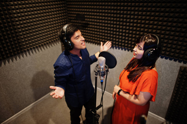 Young asian duet singers with microphone recording song in record music studio. - 写真・画像